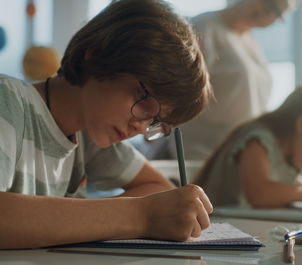 Jongen schrijft op ringblok | De VO Gids 2026