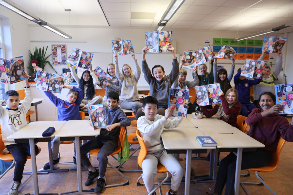 Groep kinderen in klaslokaal houdt de VO Gids 2026 omhoog