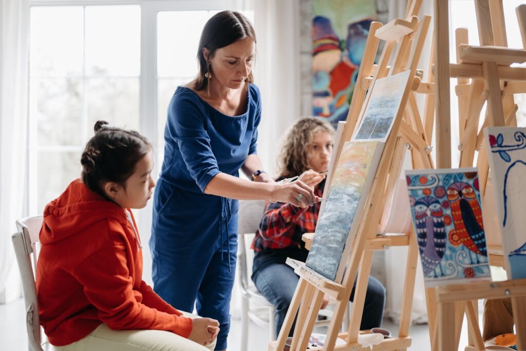 Vrouw legt kinderen achter schildersezels iets uit | De VO Gids 2026