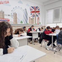Leerlingen zitten aan tafels om examen te doen in lokaal met Engelse afbeeldingen | De VO Gids 2026