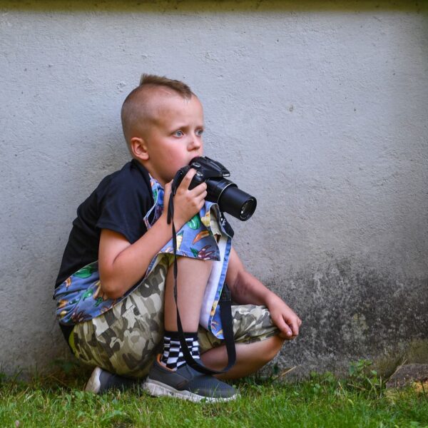 Jongen met fotocamera leunt tegen muur | De VO Gids 2027